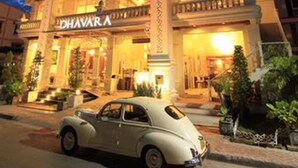Um hotel com vários andares e varandas, com um carro clássico estacionado na frente.