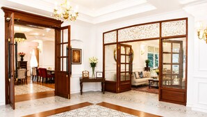 Um hall espaçoso com uma porta de madeira imponente, um tapete estampado e uma área de estar com um sofá e poltronas.
