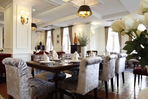 Un comedor formal con una larga mesa, numerosas sillas y una decoración elegante que incluye apliques de pared y una araña.