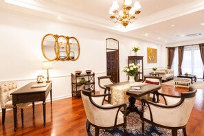 A spacious living room with a dining area, a chandelier, and a large mirror on the wall.