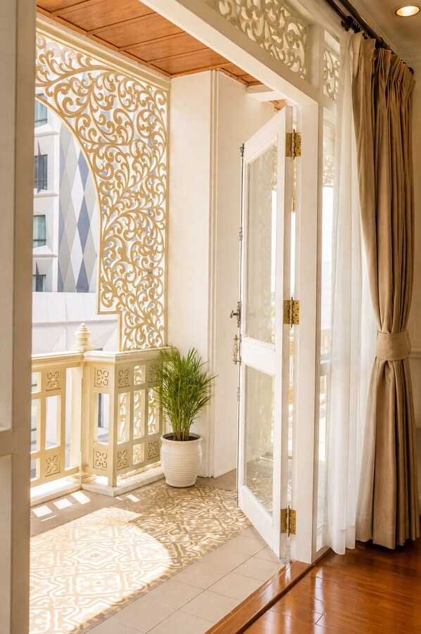 A hotel entrance with a decorative screen, a potted plant, and a patterned rug.