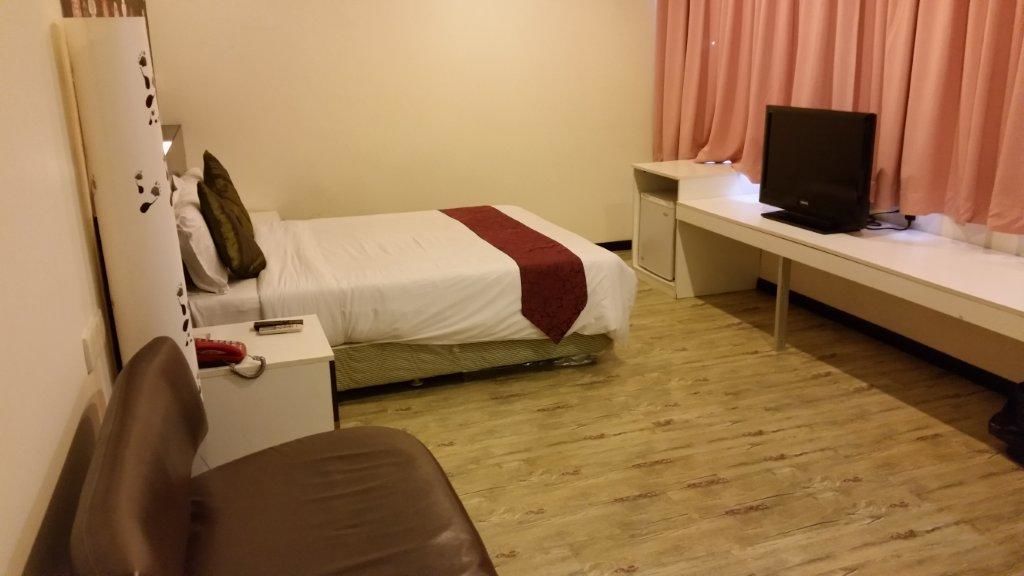 A hotel room with a bed, a desk, a television, and a chair.