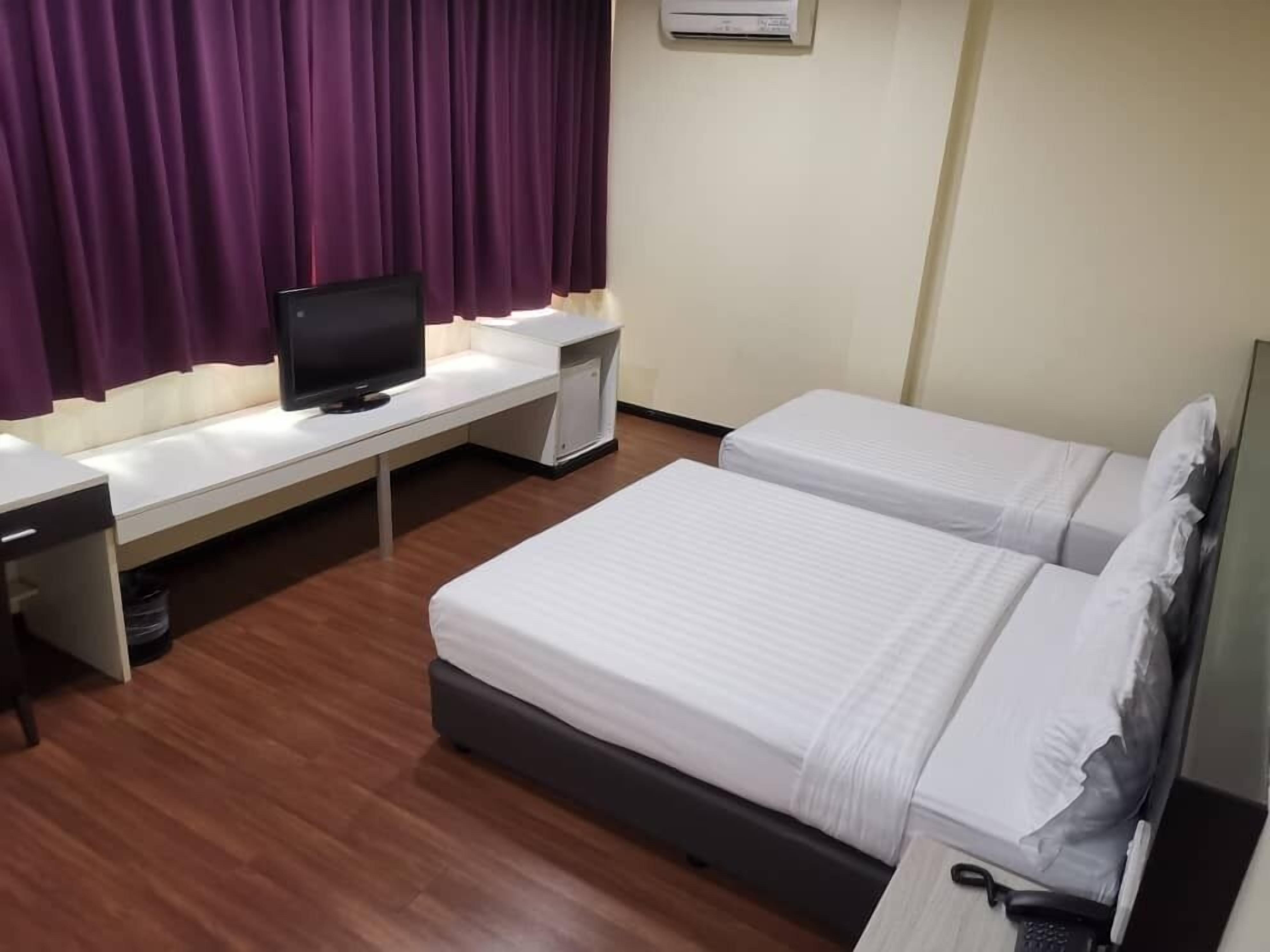 Habitación de hotel con dos camas, un escritorio, un televisor y aire acondicionado.