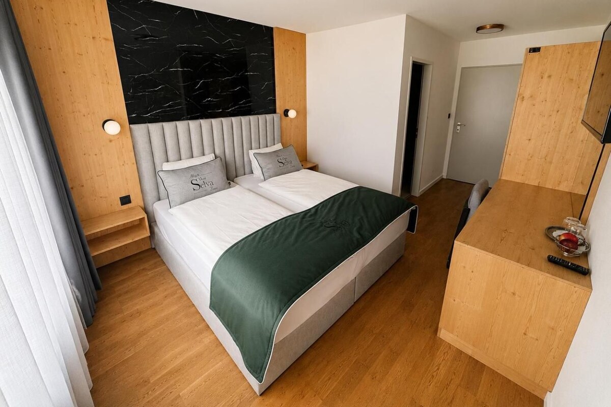 A modern bedroom with a bed, bedside tables, and a wooden wardrobe.