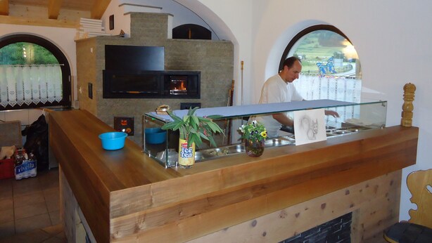 A bar area with a stone fireplace, a television, and a wooden counter.
