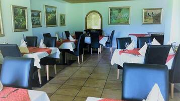 Un restaurante con varias mesas, cada una cubierta con un mantel blanco y sillas negras.