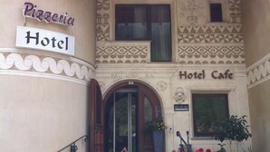A building with a sign reading "Pizzeria Hotel" and "Hotel Cafe".