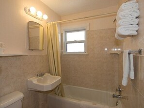 A bathroom with a bathtub, a sink, a mirror, and a window. - Blue Water Motel (Wildwood Crest)