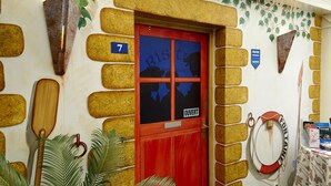 A room with a red door marked with the number 7, a life preserver, and a table with a floral tablecloth. - Hotel fontaine morlaix  (Morlaix)