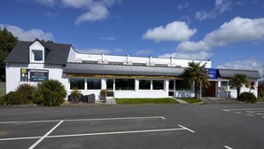 A restaurant with a white exterior, large windows, and a parking lot in front. - Hotel fontaine morlaix  (Morlaix)