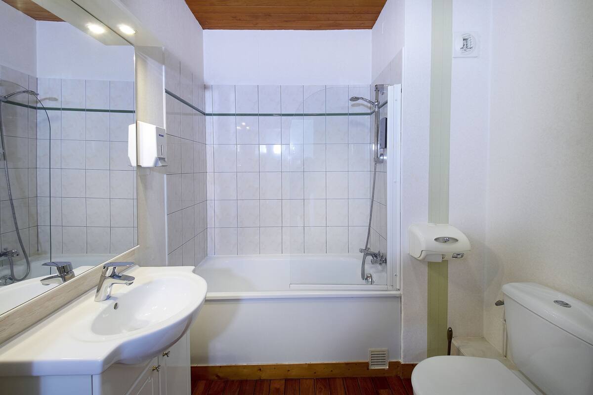 A bathroom with a white sink, mirror, and bathtub.