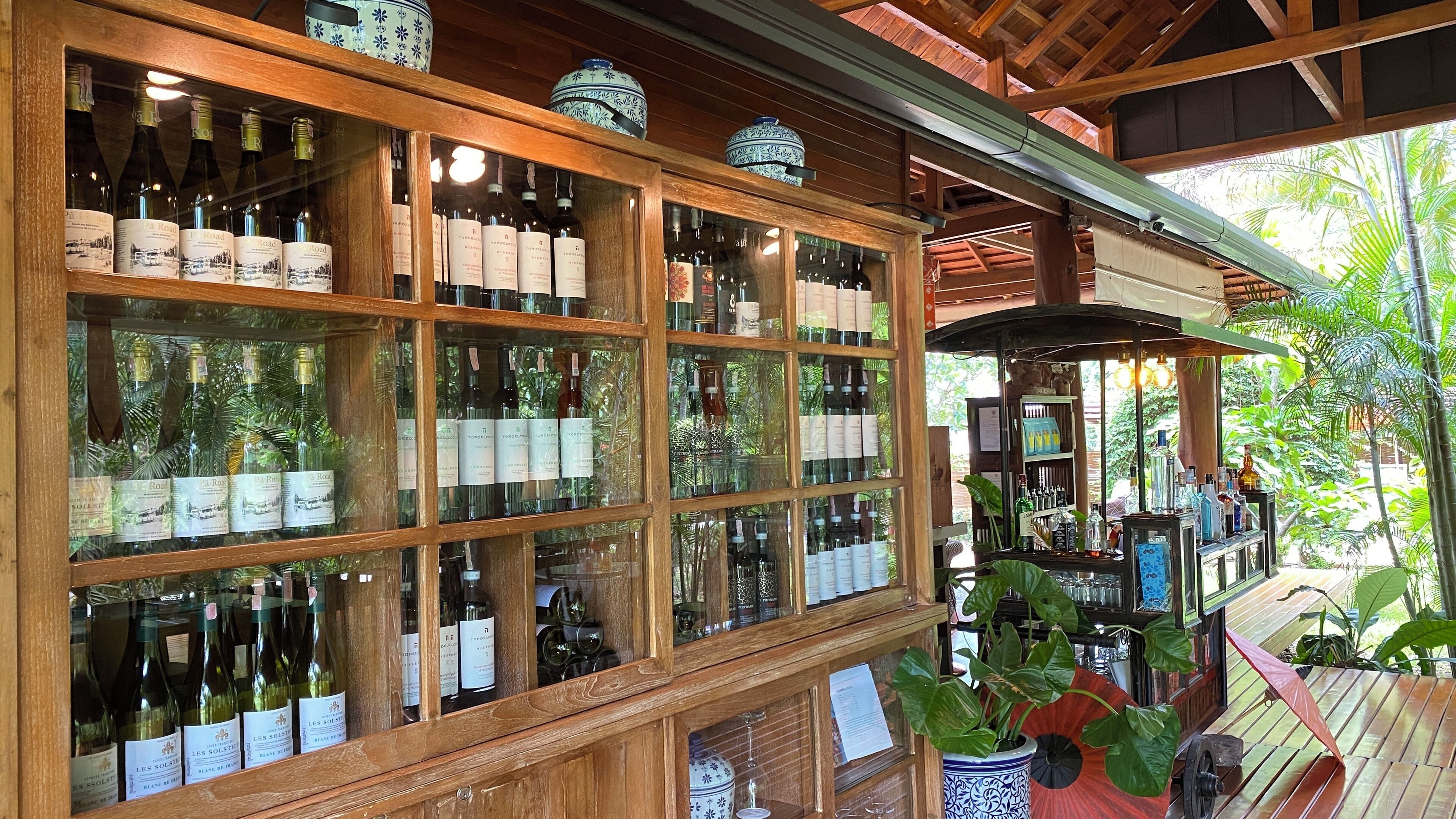 A wine cellar with wooden shelves and glass cases displaying various wine bottles.