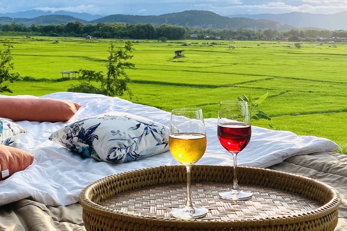 Ein Bett mit Blick auf ein grünes Feld und ferne Berge.