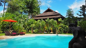 Alberca al aire libre, sombrillas en la alberca y camastros