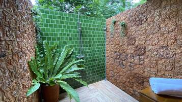 Relax in this serene space with a shower and a potted plant.
