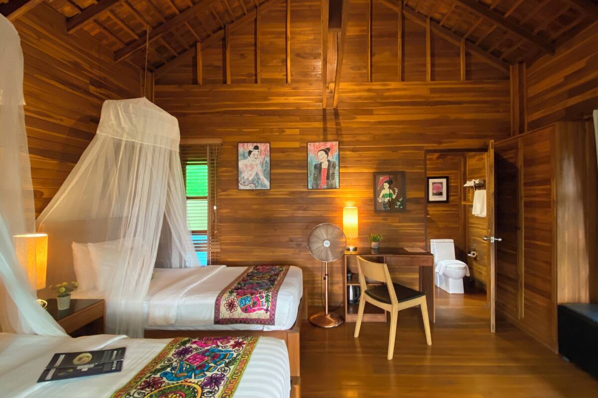 Ein Zimmer in einer Holzhütte mit einem Bett, einem Schreibtisch, einem Stuhl und einer Toilette.