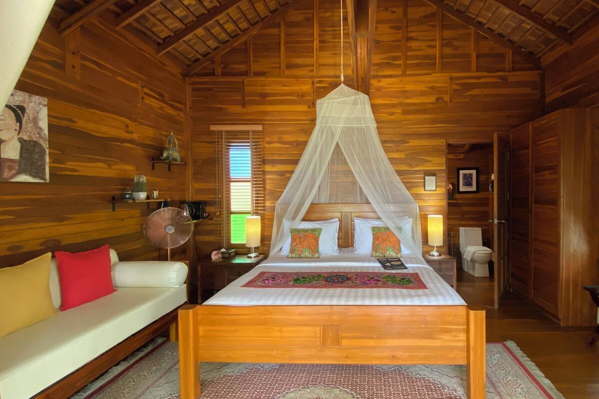 Ein Schlafzimmer einer Holzhütte mit Bett, Nachttisch, Fenster und Tür.