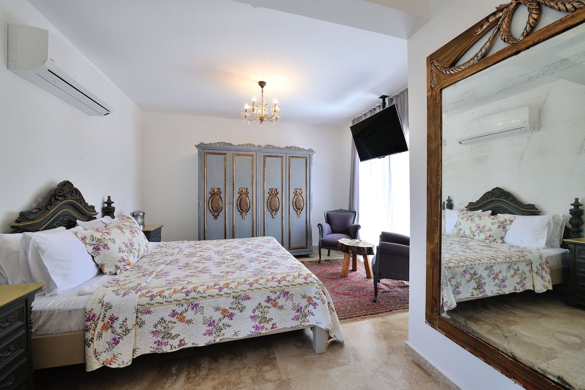 A bedroom with a bed, dresser, chair, and a large mirror.