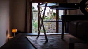 Quarto com piano, abajur e vista para um edifício histórico pela janela.