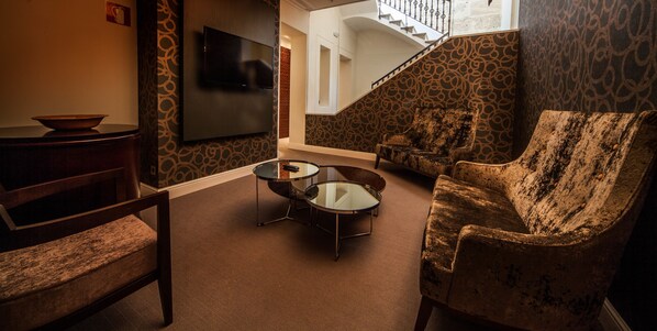 A living room with a sofa, a coffee table, and a TV mounted on the wall.
