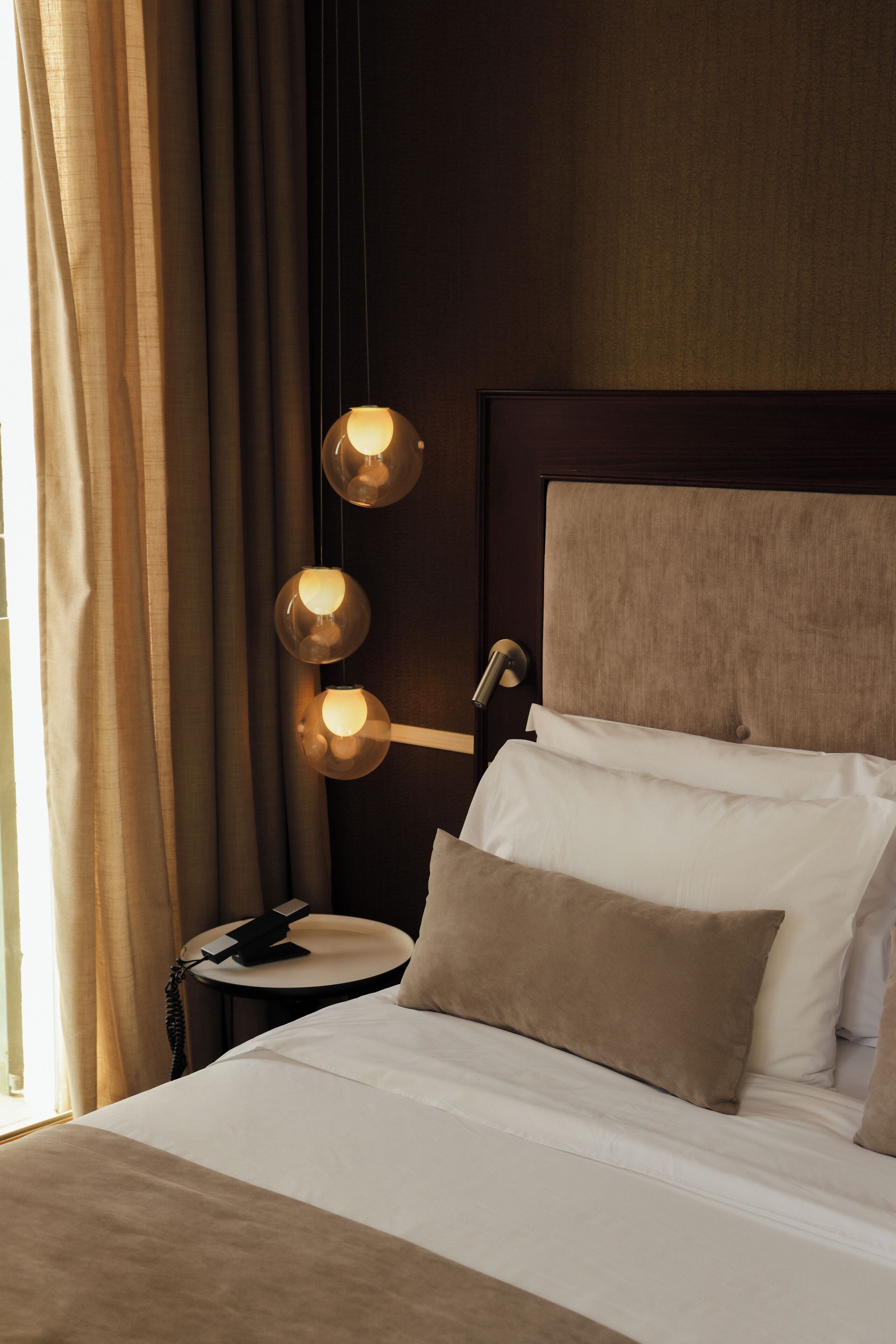 Une chambre d’hôtel avec un lit, une table de chevet avec une lampe et des rideaux.