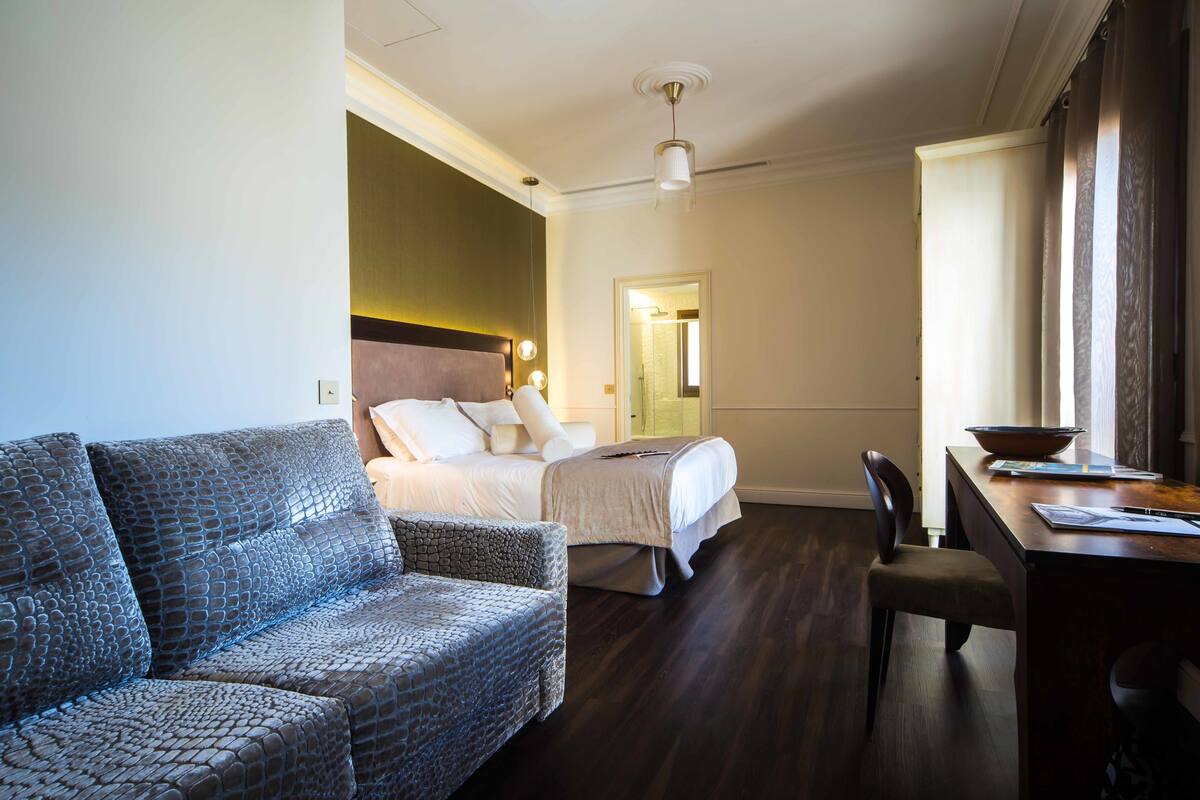 Una habitación de hotel con cama, sofá, mesa de comedor y una silla.