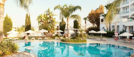 Una piscina rodeada de palmeras y sillas de descanso.