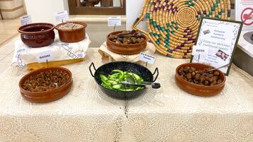 A display of various food items including walnuts, raisins, and dates, arranged on a table with a decorative woven mat and a signboard.