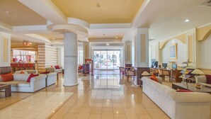 A spacious lobby with a central column, seating areas, and a view of the outdoor area. - Anesis (Ayia Napa)