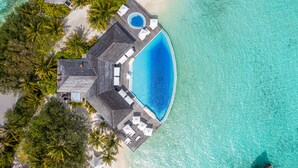 Eine Vogelperspektive auf einen luxuriösen Urlaubsort mit großem Pool, Palmen und Strand.