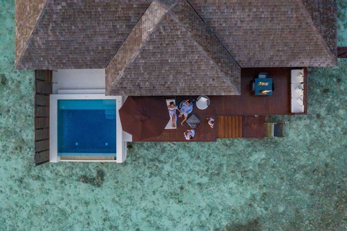 An aerial view of a resort with a swimming pool, wooden deck, and lounge area.