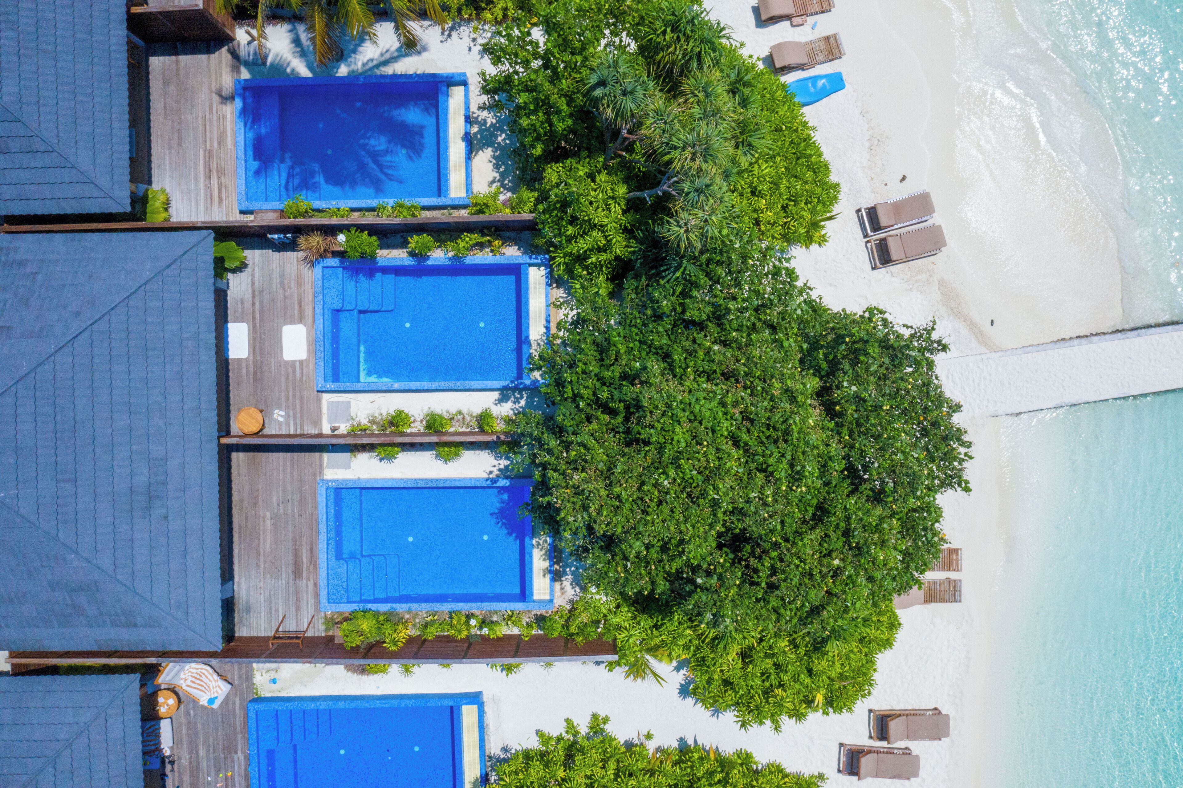 Un resort con diverse piscine, una spiaggia e una vegetazione lussureggiante.