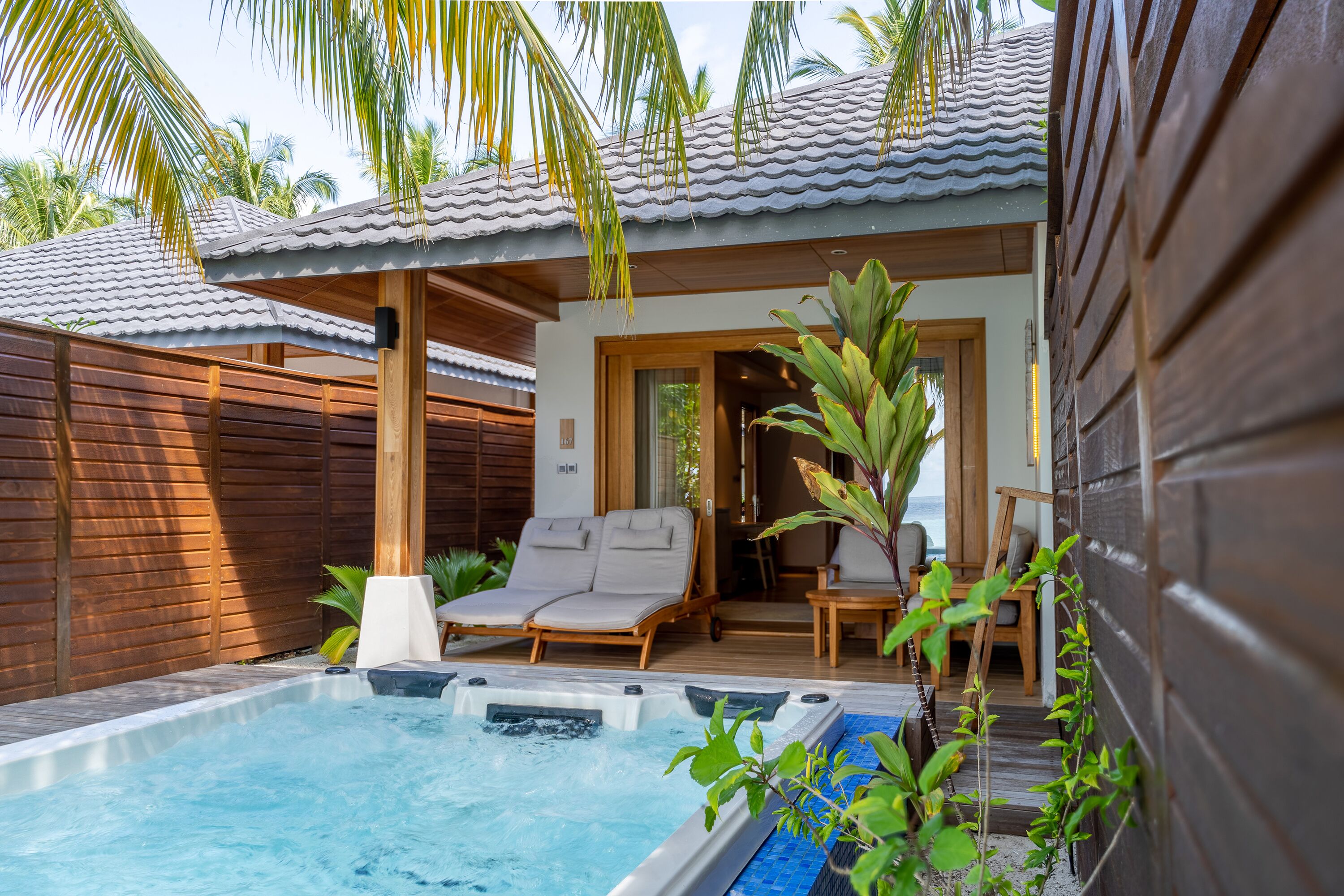 A private pool area with lounge chairs, a hot tub, and wooden deck furniture.