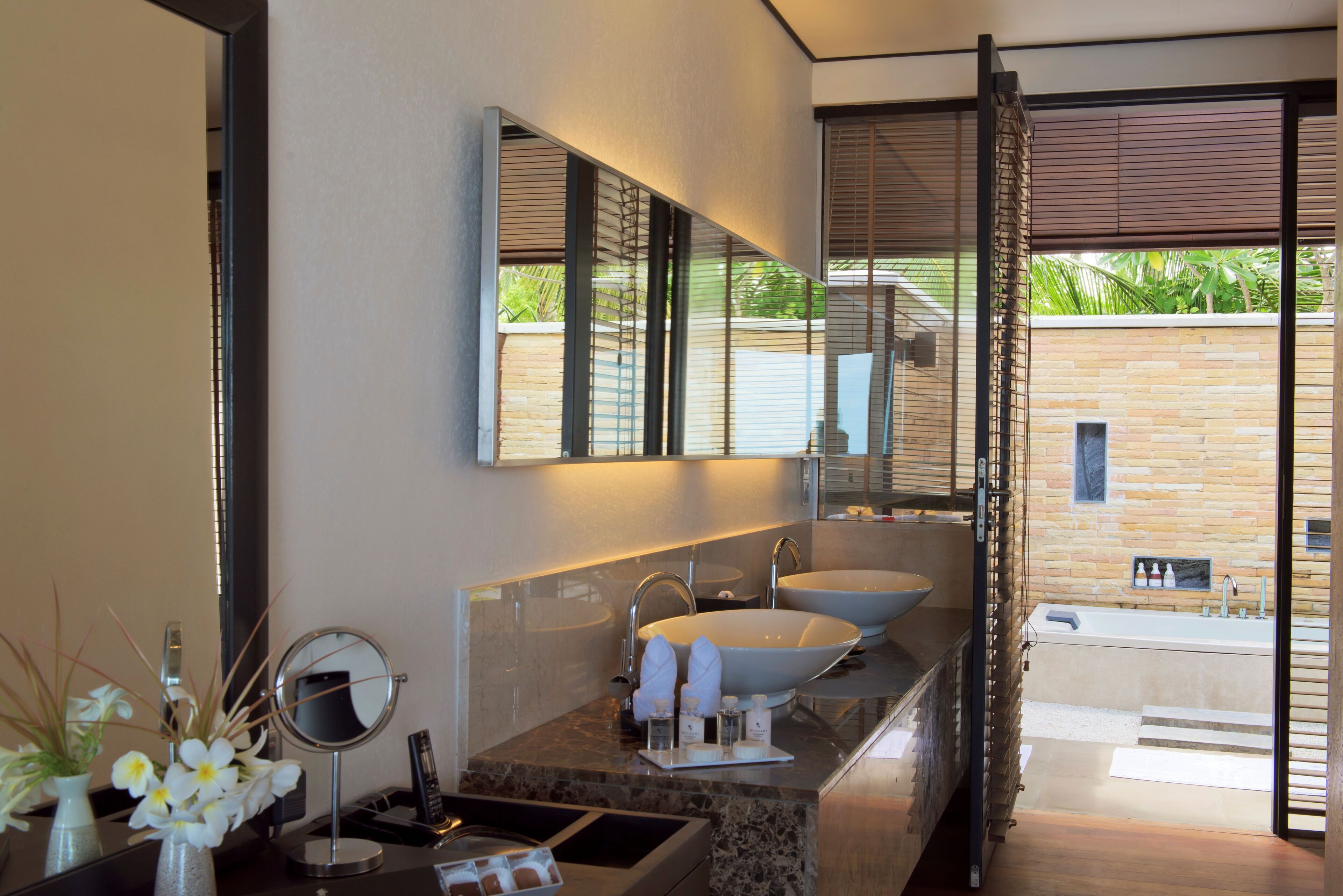 A modern bathroom with a large mirror, two sinks, and a bathtub.