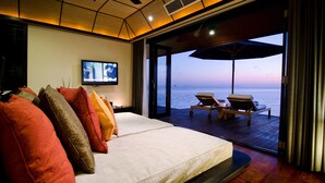 A bedroom with a large bed, a TV, and a view of the sea. - Lily Beach Resort & Spa - All Inclusive (Huvahendhoo)