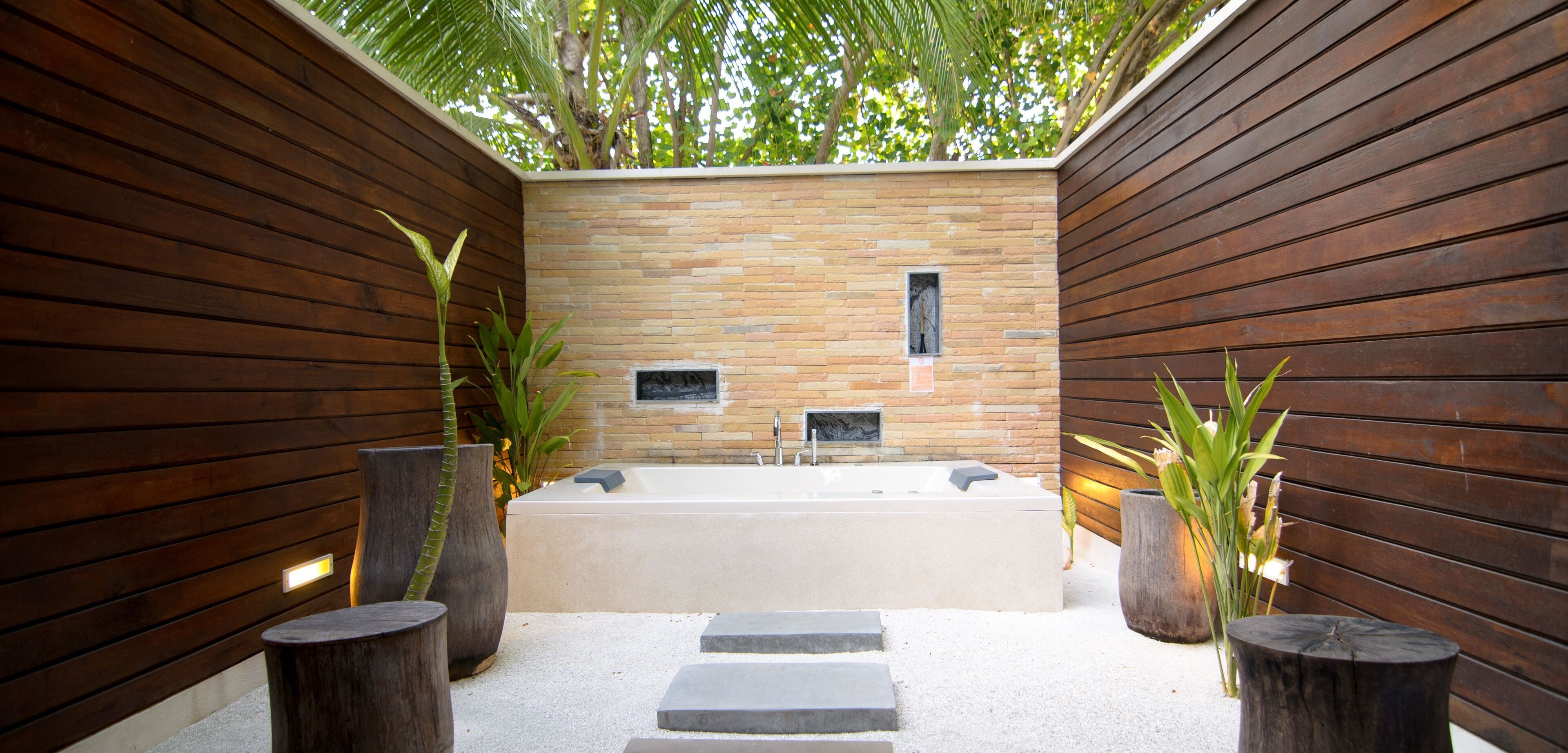 Ein moderner Wellnessbereich mit einer großen Badewanne, Holzwänden und Topfpflanzen.