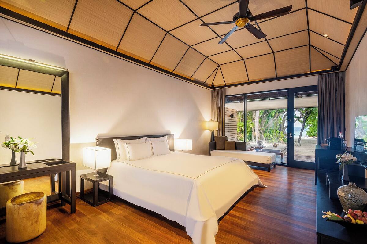 A spacious hotel room with a large bed, a desk, and a view of the beach.