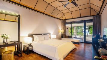 Amplia habitación de hotel con una cama grande, un escritorio y vista a la playa.