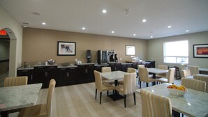A spacious kitchen with dark cabinets, a dining area with striped chairs, and a large window providing natural light. - Paradise Inn & Kitchenette Suites (Redwater)
