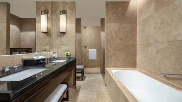 Un baño moderno con un espejo grande, dos lavamanos, una bañera y un banco.