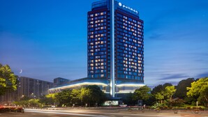 Un hôtel de grande hauteur, reconnaissable à son grand panneau « Pullman », qui se distingue par son architecture moderne, sa façade incurvée et ses nombreux balcons.