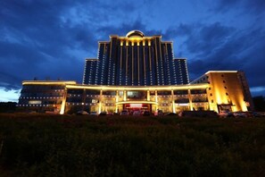 A large hotel with a central tower and multiple wings, featuring a grand entrance and a well-lit facade.