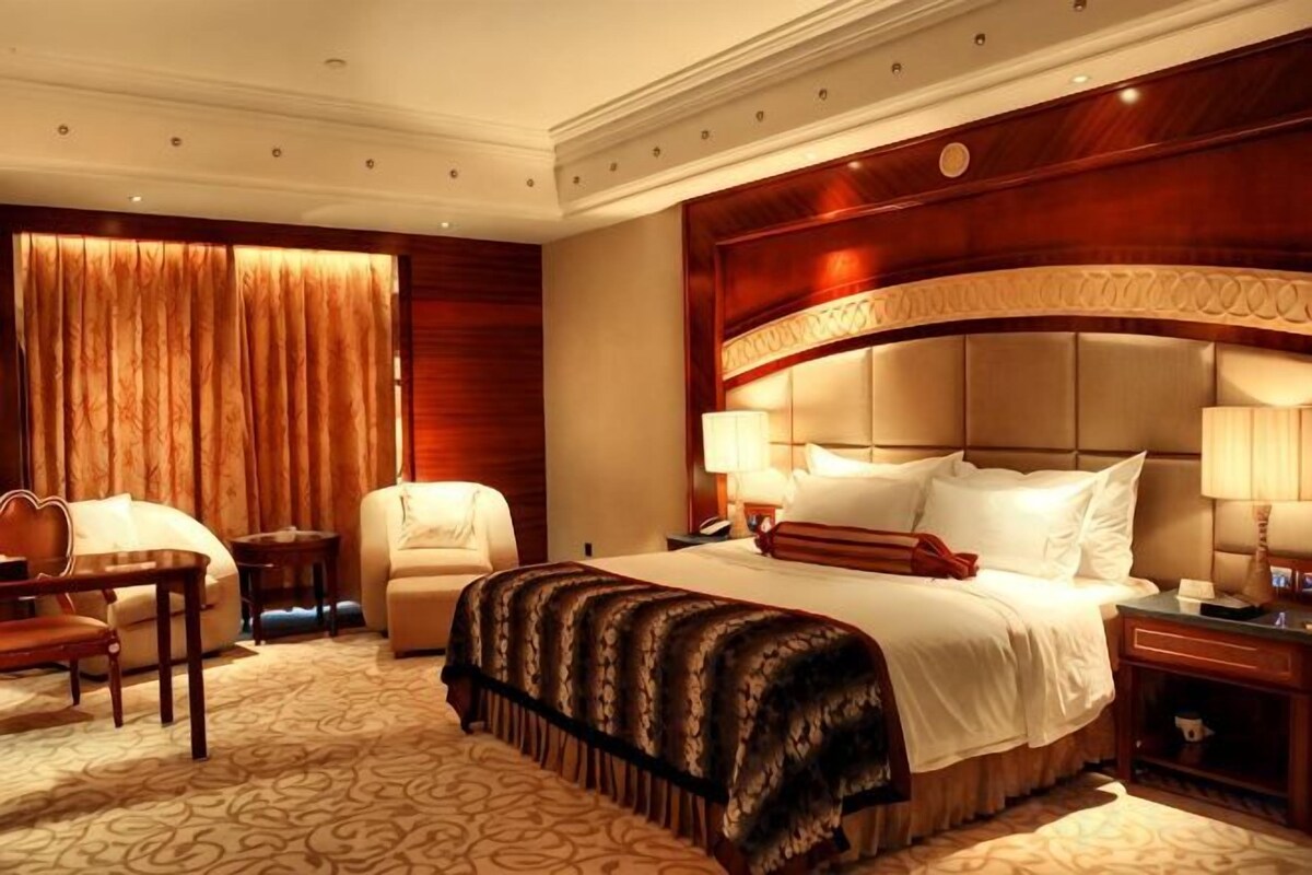 A hotel room with a large bed, a desk, a chair, and a nightstand.