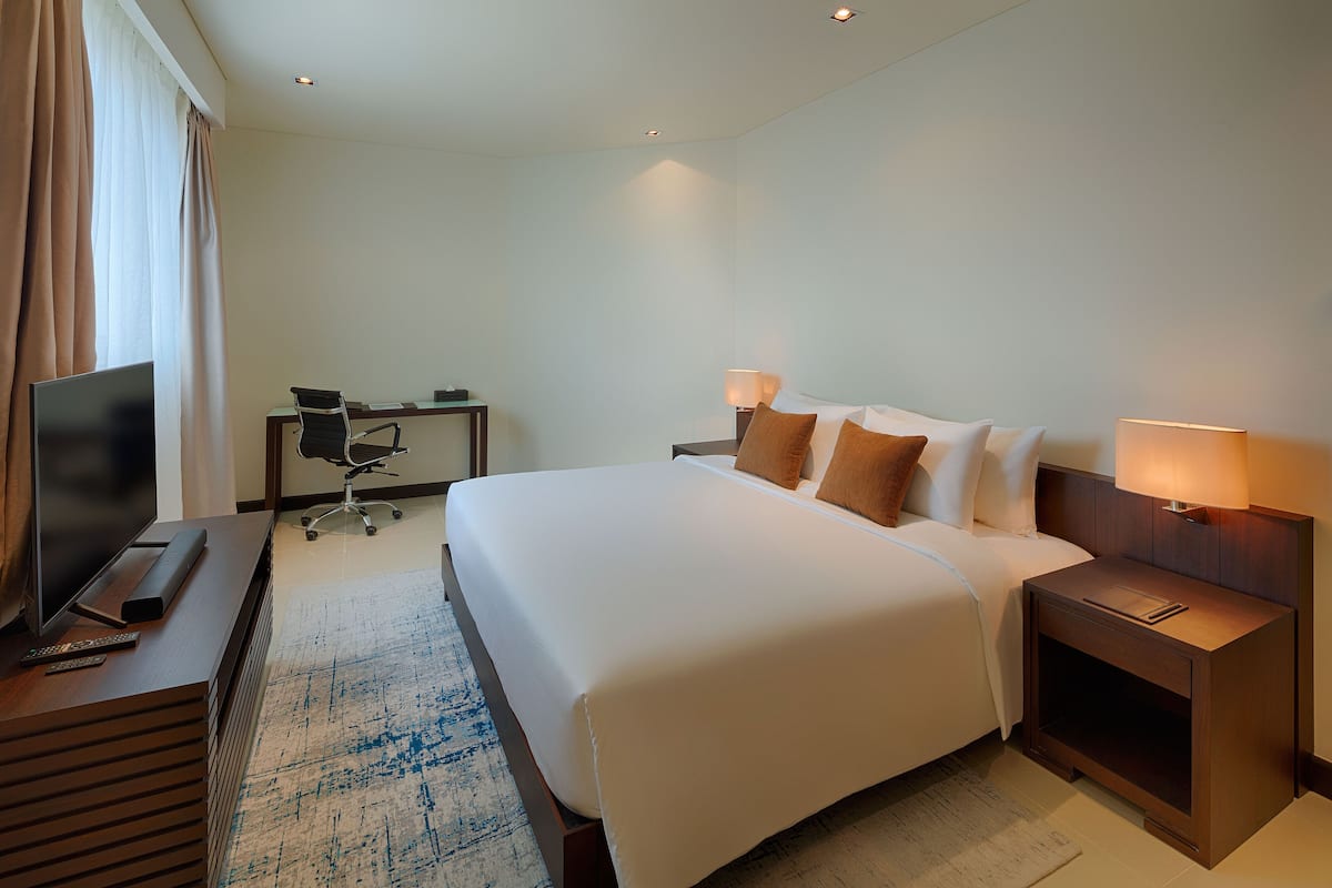 Een hotelkamer met een bed, nachtkastjes, een bureau, een televisie en een afstandsbediening.