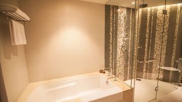 A modern bathroom with a large bathtub, a glass-enclosed shower, and a tiled shower wall.