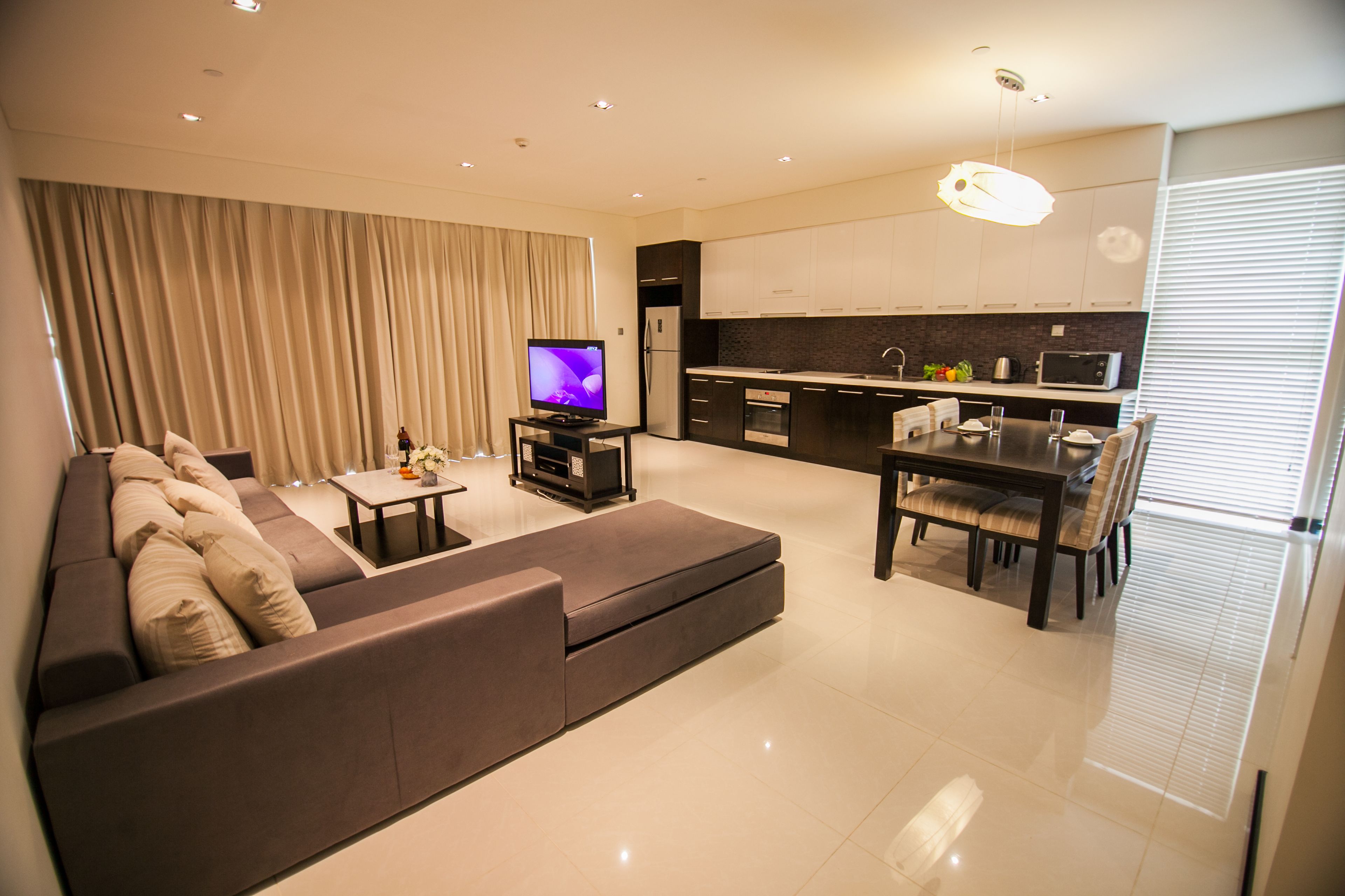 Een moderne woonkamer met een bank, televisie en een eethoek.