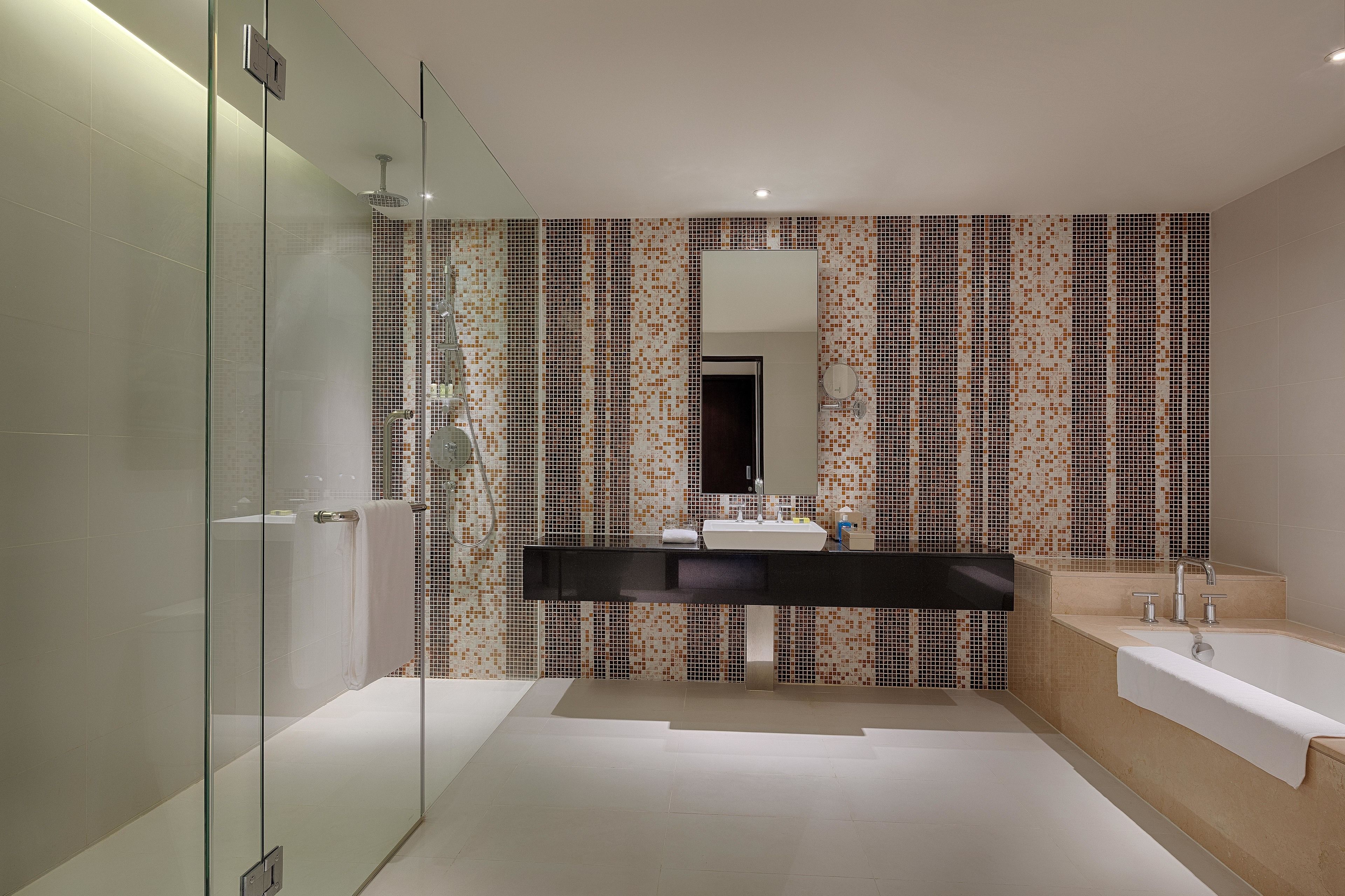 Une salle de bain moderne avec une douche à l’italienne en verre, un meuble-lavabo noir et une baignoire beige.