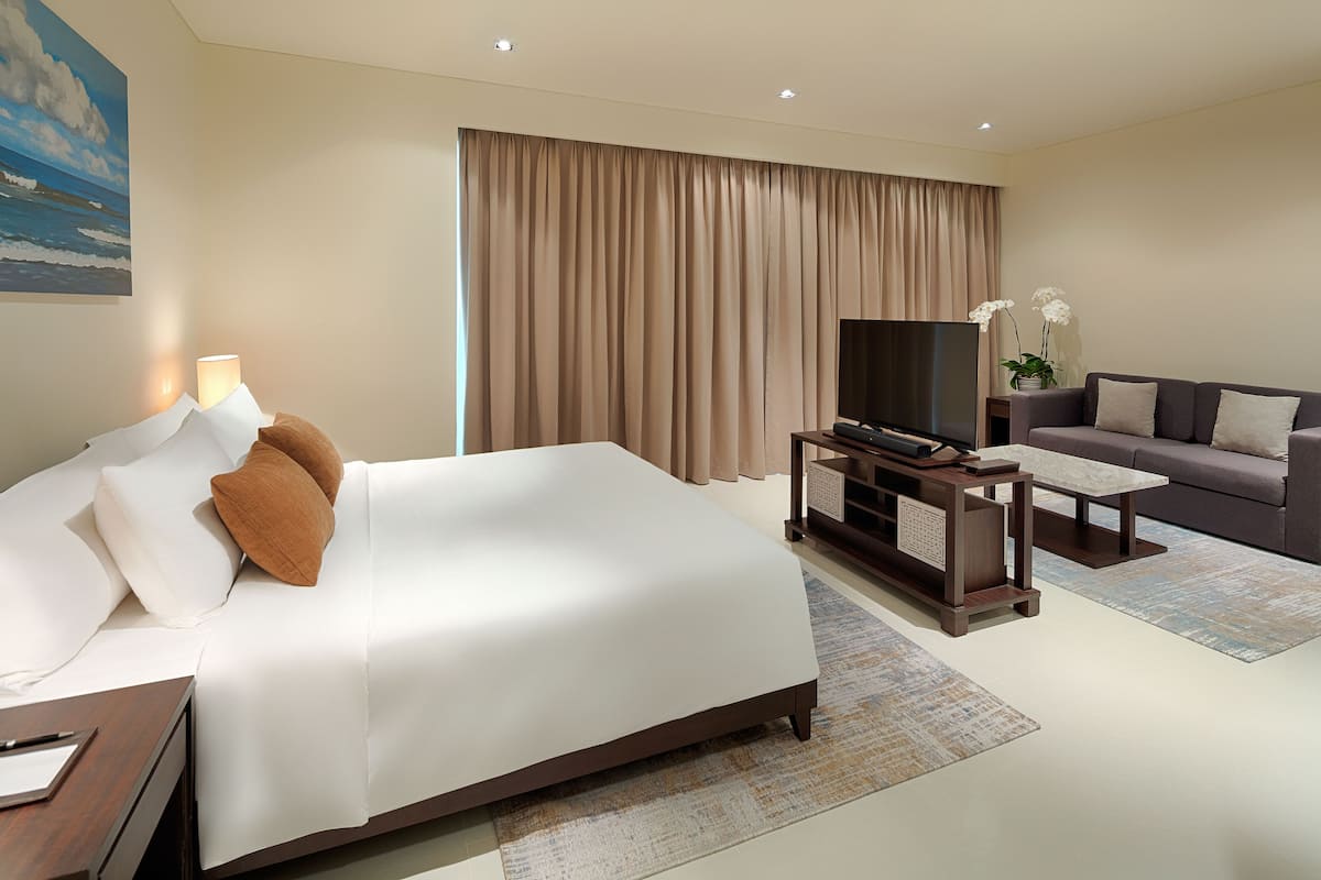 Een hotelkamer met een groot bed, een televisie, een bank en een bureau.