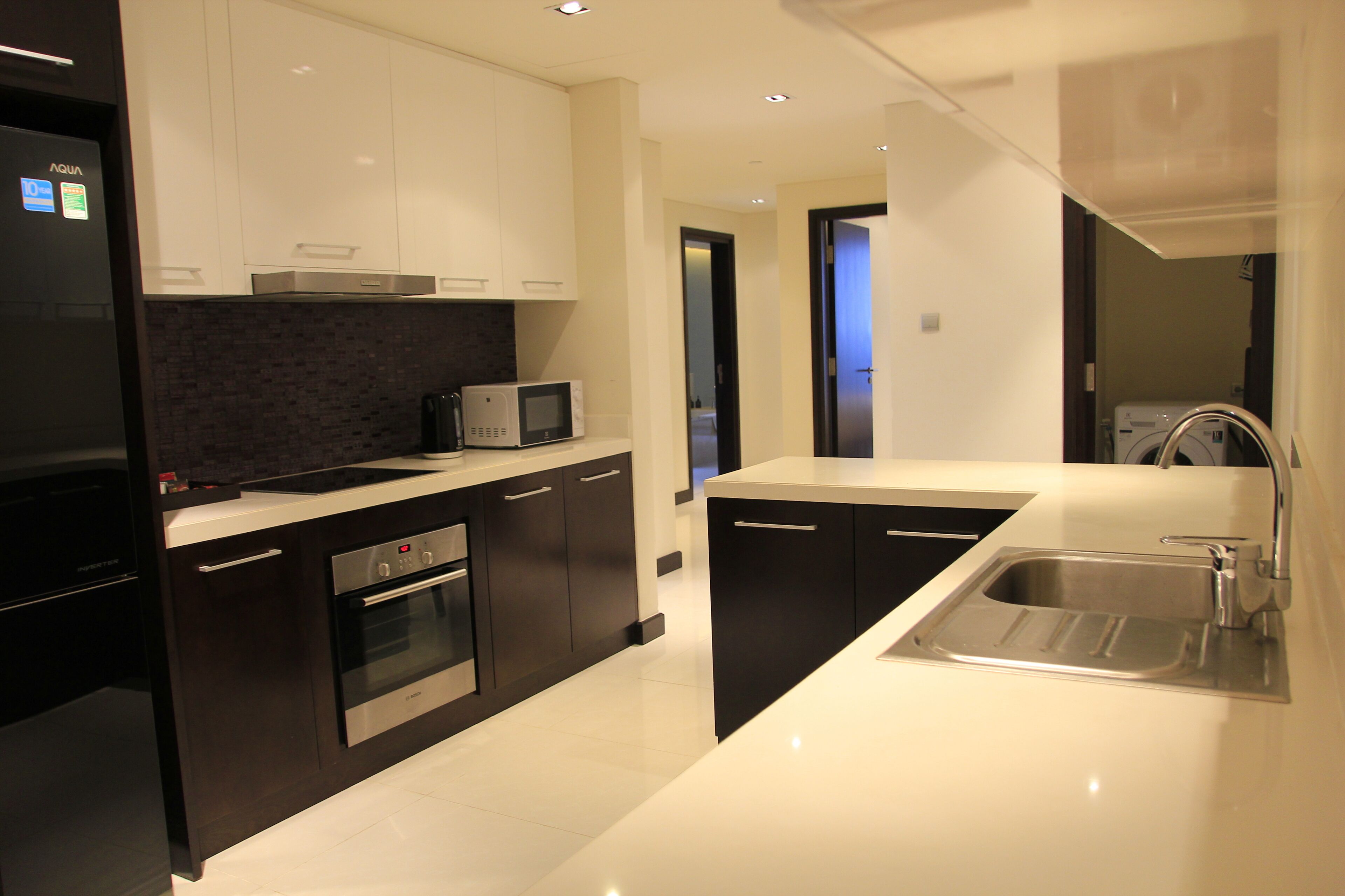 A modern kitchen with dark cabinetry, a stainless steel sink, and a built-in microwave.