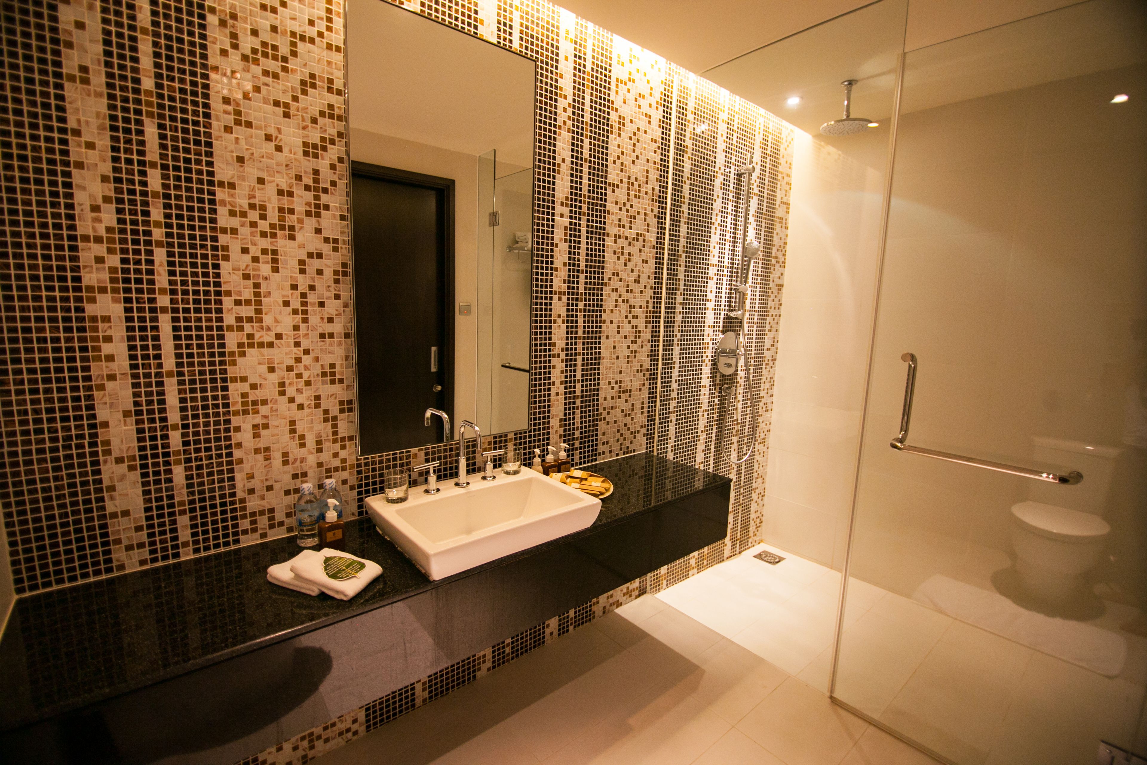 A modern bathroom with a large mirror, a sink, and a shower area.